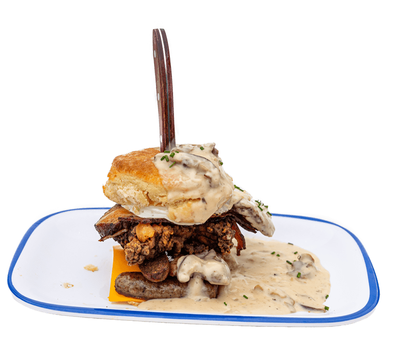 Cut out picture of a biscuit sandwich with sausage, cheese, fried chicken, egg, and gravy with a knife stuck through the top