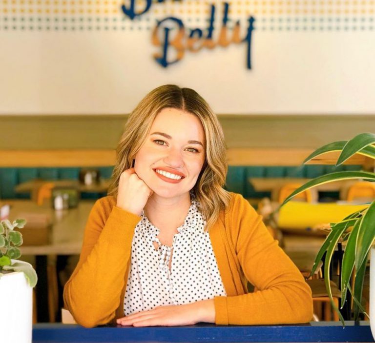 Picture of woman in yellow sweater smiling inside Biscuit Belly restaurant