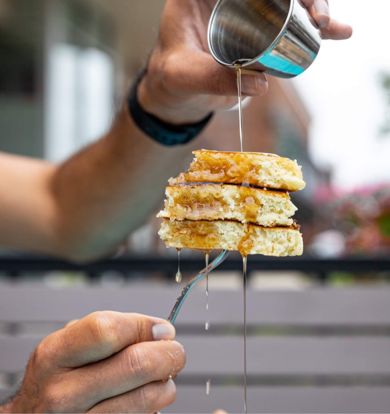 Picture of syrup being poured onto a fork full of fluffy pancakes
