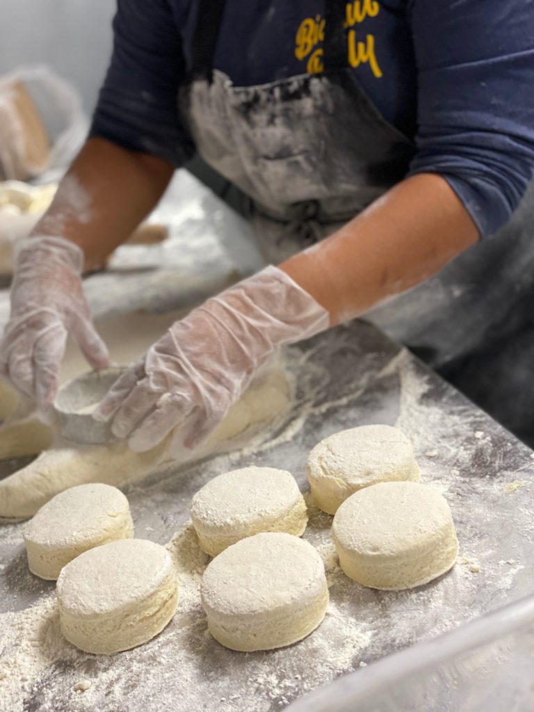 Cook in black apron prepares biscuits for the oven