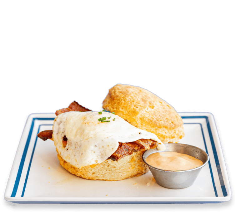 Cut out picture of a bacon and egg biscuit sandwich with a side of sauce