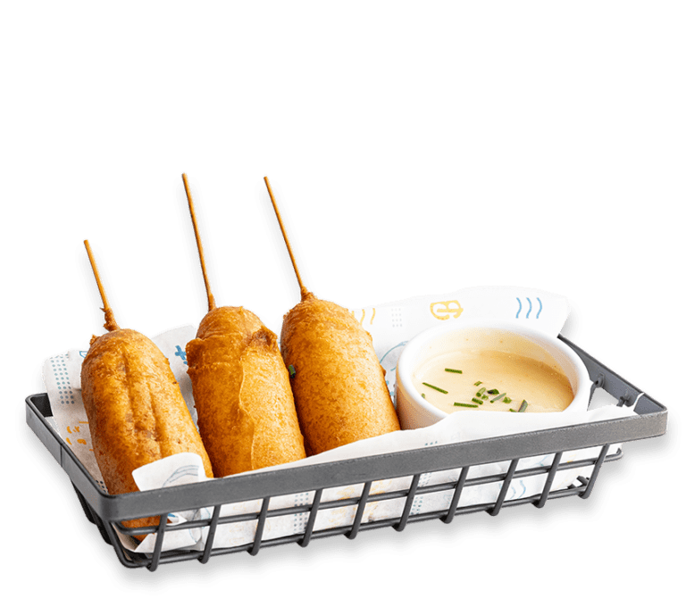 Cut out picture of pancake corndogs with a side of sauce in a metal basket