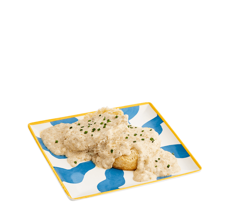 a single, open-faced biscuit smothered with sausage gravy and topped with chopped green chives on a blue and white striped plate