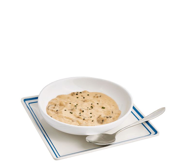 mushroom gravy in a large white bowl sitting on a white plate with a blue border and a spoon on the side