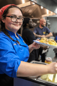 Hannah McClain smiles at the camera as she serves up a plate of biscuits and gravy.