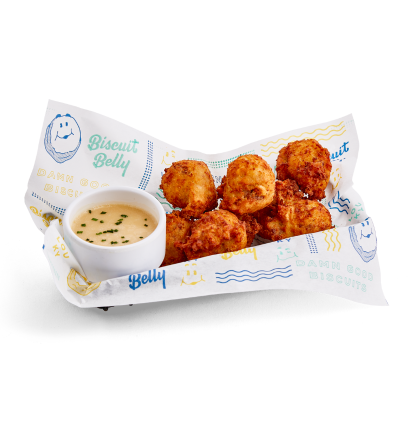A lined basket with Loaded Breakfast Tots and a Maple Mayo sauce in a white ramekin.